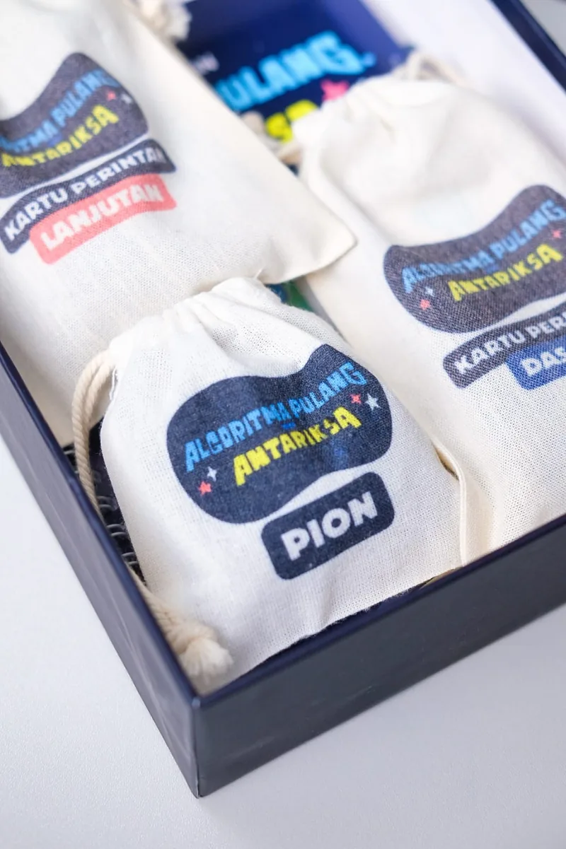 Tiga kantong kain komponen permainan dengan label PION dan BONUS.